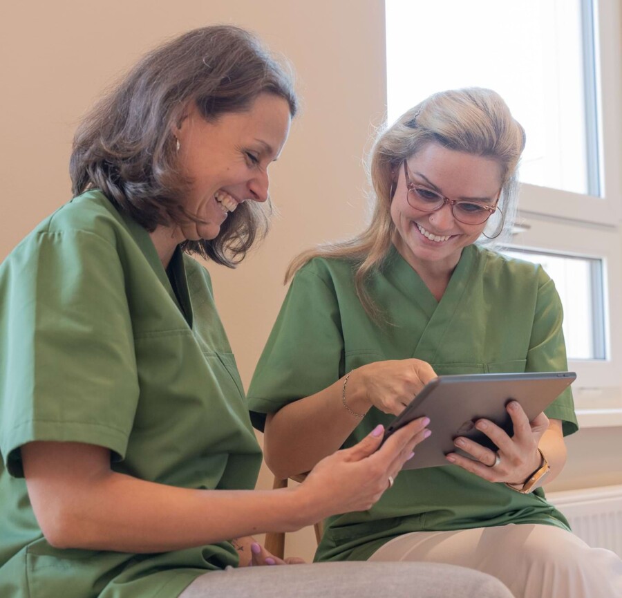 Fotoaufnahme: Zwei Mitarbeiterinnen arbeiten gemeinsam an einem Tablet